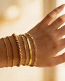 Stacked gold-tone chain bracelets on a wrist