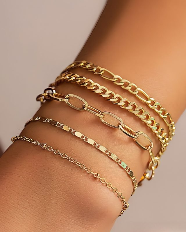 Stacked gold-tone chain bracelets on a wrist