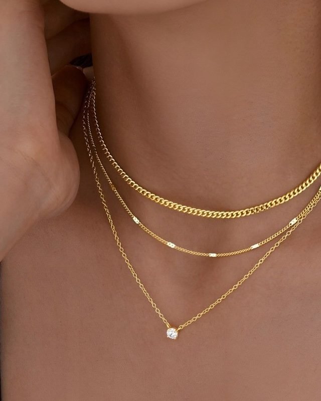Layered gold-tone necklaces at the collarbone