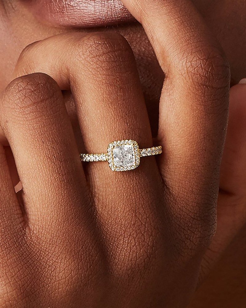 Gold-tone ring with a square stone on a hand