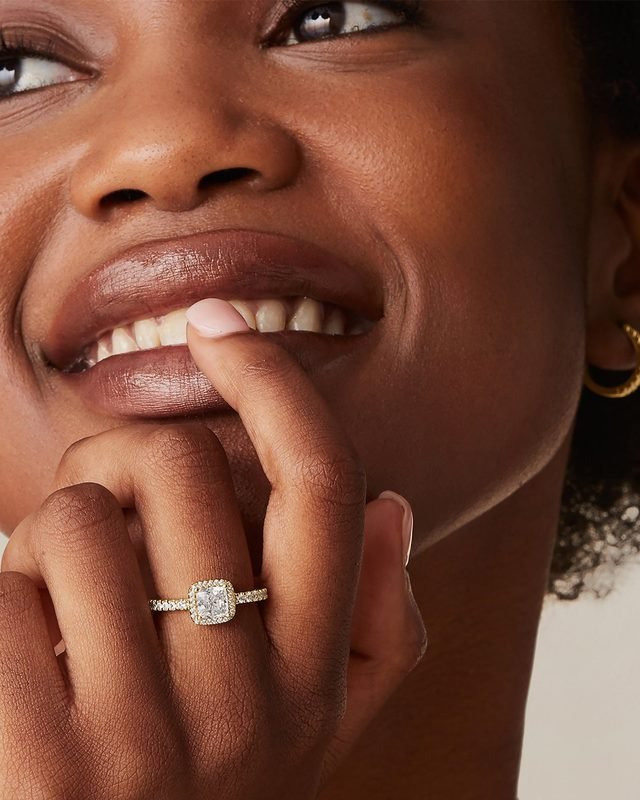 Gold-tone halo ring with a square stone, worn on the finger